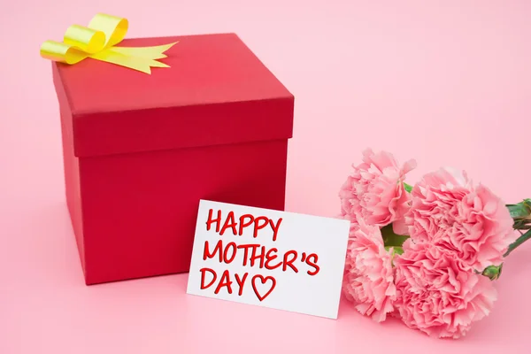 Cartão de dia feliz da mãe e caixa de presente vermelho e cravos rosa — Fotografia de Stock