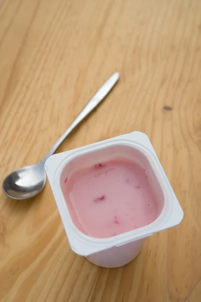 Aardbei smaak yoghurt op houten tafel — Stockfoto