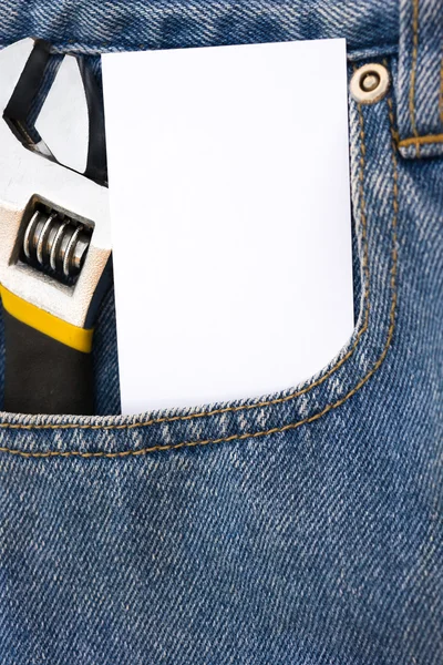 Порожня картка і гайковий ключ на синьому джинсі — стокове фото