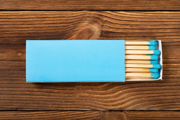 木製のテーブルの上に青いマッチ棒付きの青い色のマッチ箱を表示 — ストック写真