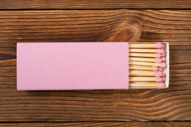 Üst manzara pembe kibrit kutusu ve ahşap bir masada pembe kibrit çöpü.