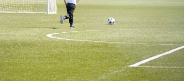 Sahada futbol oynayan bir çocuk.