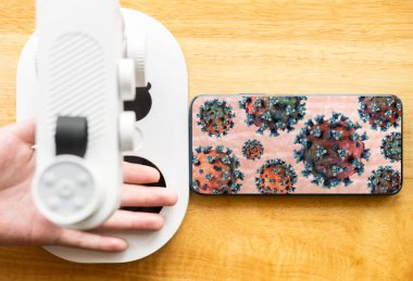 Çocuk eline kablosuz internet mikroskobuyla bakıyor ve bir sürü koronavirüs görüyor.