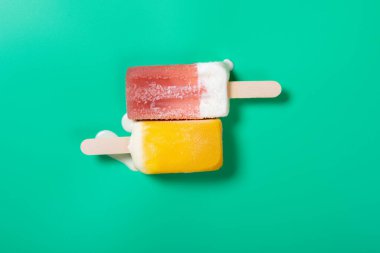 Üst görünüm iki canlı renkli çubuk yeşil arkaplanda erimeye başlar