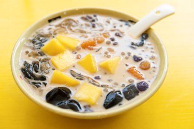 Bir kase sütlü çay aromalı mango, tatlı patates, sago ve siyah jöle.