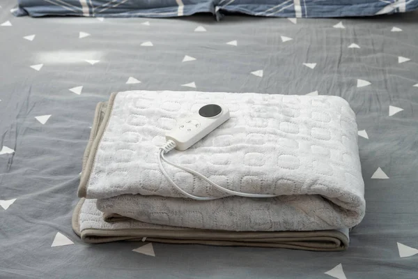 folded electric blanket with controller on the bed at horizontal composition