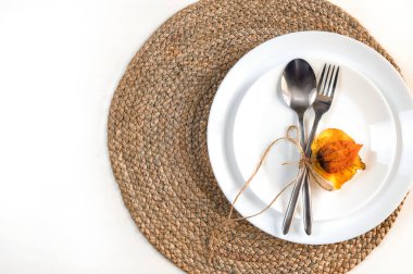 Sonbahar yaprakları, çatal ve bıçak beyaz bir tabakta.