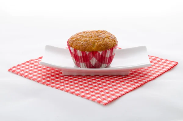 Kırmızı desenli peçete ve plaka üzerinde bir cupcake