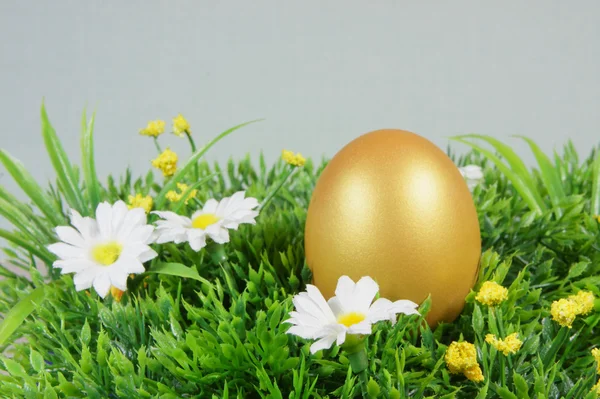 Ägg på ett grönt konstgräs med vita blommor — Stockfoto