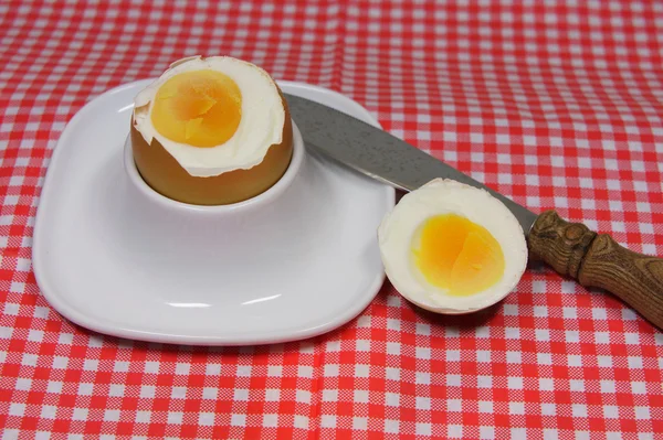 Golden egg in an egg cup on a red patterned napkin with spoon — Stock Photo, Image