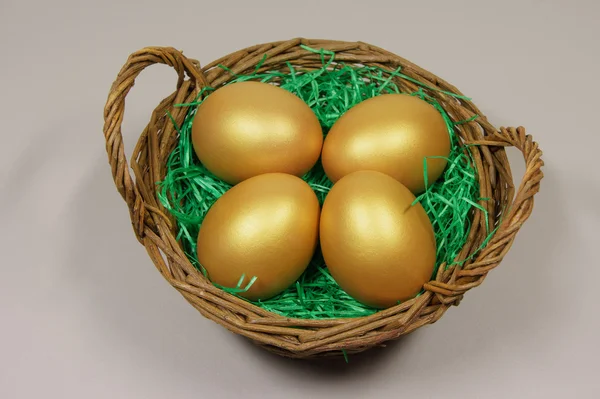 Four golden eggs in basket on green grass — Stock Photo, Image