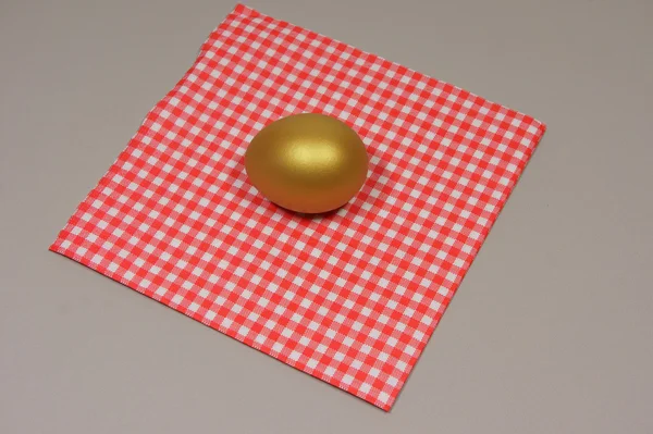 Golden egg on a patterned napkin — Stock Photo, Image