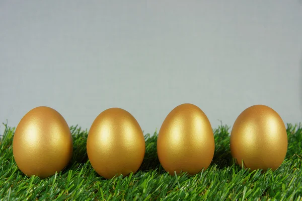 Golden eggs on a green artificial turf — Stock Photo, Image