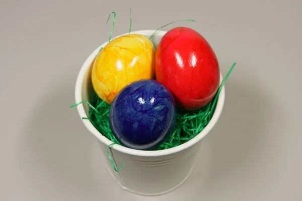 Färgglada ägg i en skål med grönt gräs — Stockfoto