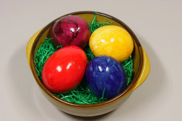 Colorful eggs in a bowl with green grass — Stock Photo, Image