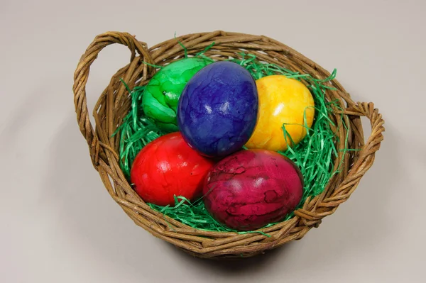 Colorful eggs in a basket with green grass — Stock Photo, Image