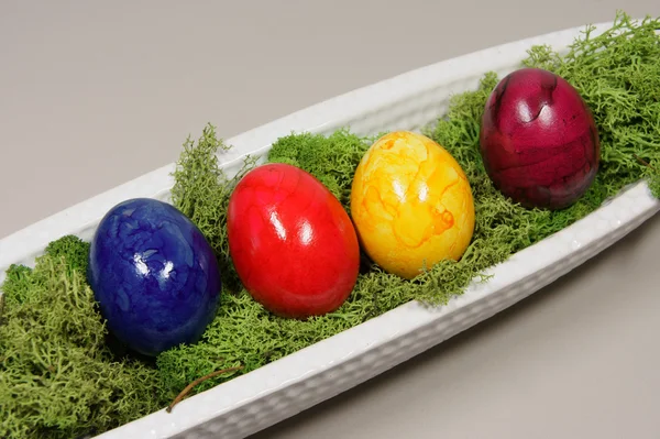 Красочные яйца в удлиненной белой чаше — стоковое фото