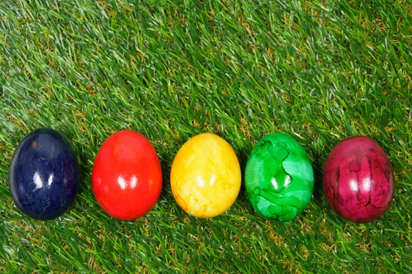 Huevos de colores se encuentran en un césped sintético — Foto de Stock