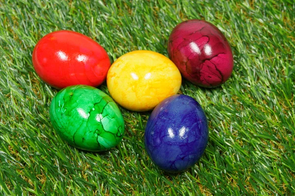 Huevos de colores se encuentran en un césped sintético — Foto de Stock