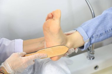 Genç bir kadın güzellik salonunda profesyonel pedikür yaptırıyor.