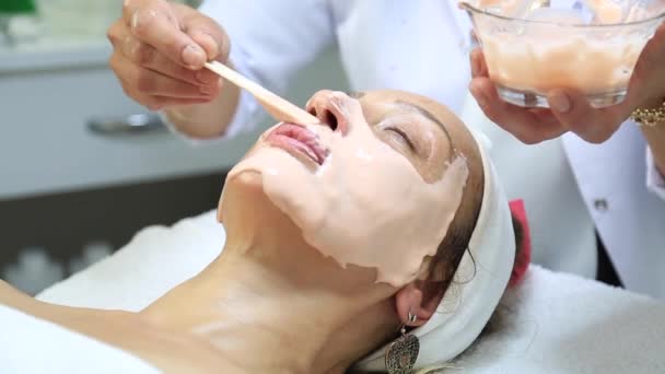 面部剥皮面膜 温泉美容治疗 皮肤护理 在温泉沙龙接受美容美发治疗的妇女 侧视近视 美容院给美女做面部按摩 — 图库视频影像