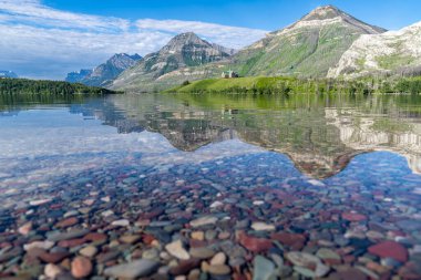 Colorful rocks on Driftwood Beach, with relfection of the Prince of Wales hotel in Waterton Lakes National Park Canada