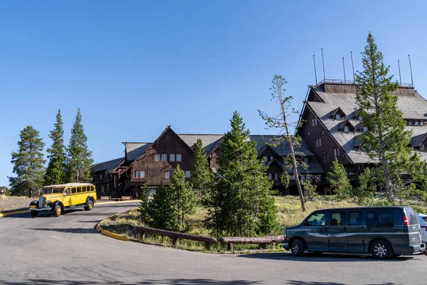 Wyoming, USA - July 18, 2022: The Old Faithful Inn as a old fashioned yellow bus pulls away with a tour group