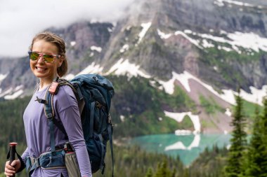 Woman hiker takes a moment to enjoy the scenery along the Grinnell Glacier Hike in Glacier National Park Montana
