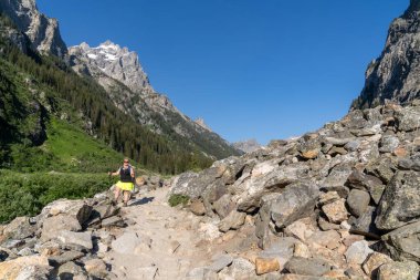 Grand Teton Ulusal Parkı 'ndaki Cascade Canyon yolunda sırt çantalı bir kadın yürüyüşçü.