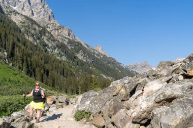 Grand Teton Ulusal Parkı 'ndaki Cascade Canyon yolunda sırt çantalı bir kadın yürüyüşçü. Sol hizalı, kopyalama alanı