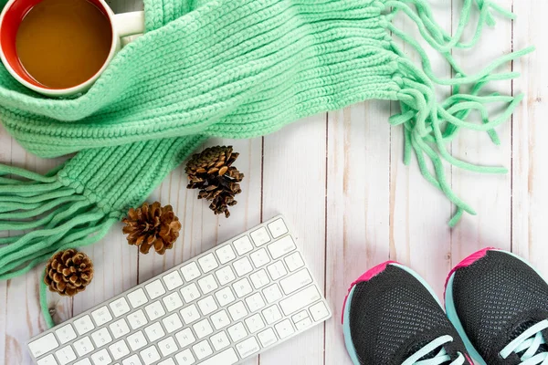Running blogger fall cozy sweater weather autumn arrangement, with white keyboard, pine cones, cable knit teal scarf, sneakers, coffee mug on wood background