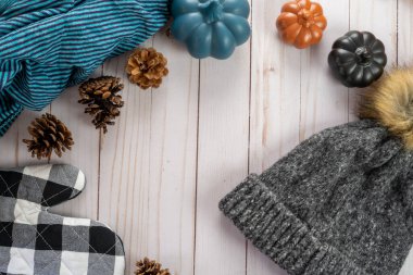 Kış şapkası, renkli balkabağı, fırın eldiveni, kozalak ve ahşap arka planda mavi battaniye ile sonbahar konsepti.