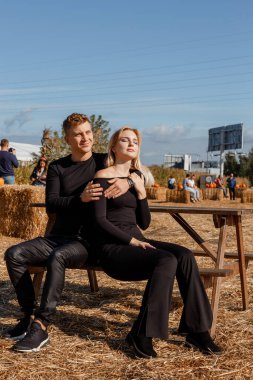 Çiftlikte oturan genç bir çift. Aşık genç çift oturuyor ve kameraya bakıyor..