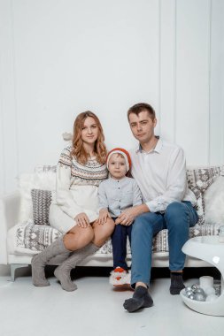 Yeni yıl için stüdyoda küçük çocukla bir aile. Ailesi ve oğlu Noel fotoğraf çekimindeymiş. Tatilden önce stüdyo çekimi. Mutlu Noeller ve mutlu tatiller.