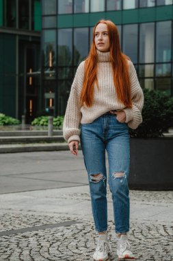 Başarılı mutlu kadın portresi işe giderken yolda. Şehir sokaklarında poz veren çok uzun saçlı, güzel, doğal kızıl saçlı bir kızın açık hava portresi. Uzun kızıl saçlı moda kızı..