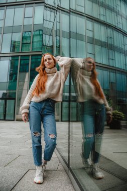 Başarılı mutlu kadın portresi işe giderken yolda. Şehir sokaklarında poz veren çok uzun saçlı, güzel, doğal kızıl saçlı bir kızın açık hava portresi. Uzun kızıl saçlı moda kızı..