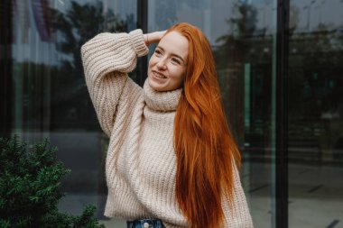 Başarılı mutlu kadın portresi işe giderken yolda. Şehir sokaklarında poz veren çok uzun saçlı, güzel, doğal kızıl saçlı bir kızın açık hava portresi. Uzun kızıl saçlı moda kızı..