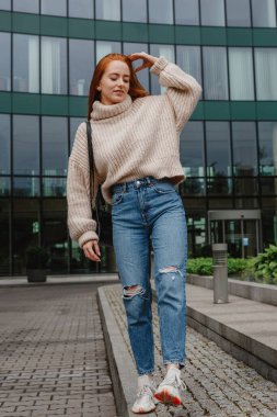 Kızıl saçlı, şık bir genç kadının yan resimleri. Şehir yaşam tarzı konsepti. İş merkezine yakın modern bir kadın. Varşova.