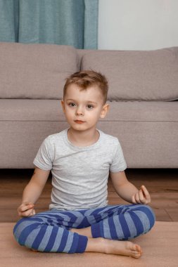 Çocuk Lotus pozu veriyor ve birlikte gülümsüyor. Yoga meditasyonunda gülümseyen çocuğun portresi. Çocuk ve yoga.