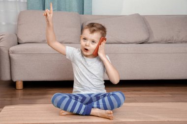 Çocuk telefonda konuşuyor. Şirin Çocuk cep telefonuyla oynuyor. Akıllı telefon kullanan küçük bir çocuk elini ve parmağını kenarda göstererek çok mutlu olur..