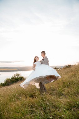 Pretty bride and stylish groom. Beautifull wedding couple embracing near the shore of a mountain river with stones. Wedding at Bakota.