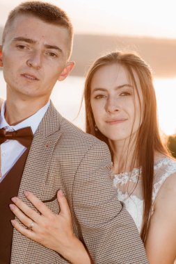 Pretty bride and stylish groom. Beautifull wedding couple embracing near the shore of a mountain river with stones. Wedding at Bakota.