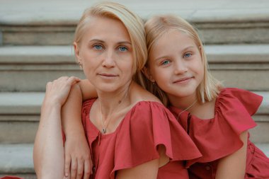 Annesini seven esmer, heyecanlı bir kız. Şık kırmızı elbiseli güzel bir genç kadının portresi..