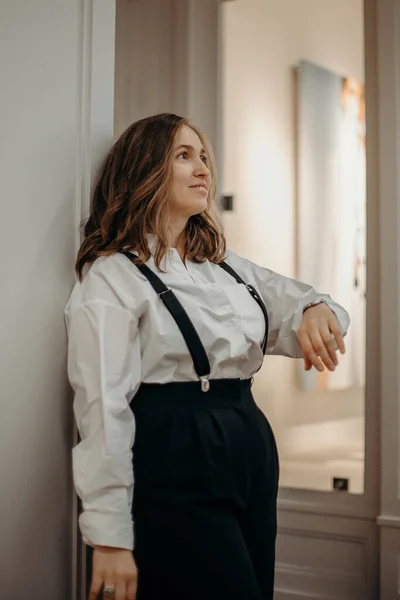 Portrait of fashion retro girl in white shirt, suspenders and black wide pants. Copy, empty space for text. Beautiful woman wearing elegant vintage outfit, posing.