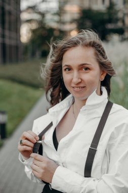 Beyaz gömlekli, pantolon askısı ve siyah geniş pantolonlu modacı kız portresi. Anlaşıldı, metin için boşluk. Güzel bir kadın şık bir elbise giyiyor, poz veriyor..