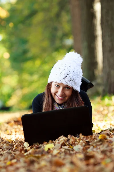 Ragazza carina con computer portatile nel parco autunnale. Adolescente europeo — Foto Stock