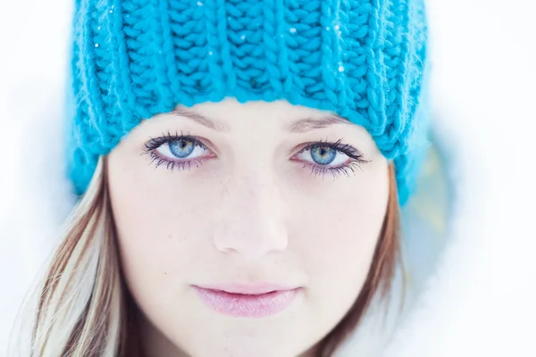 Porträt eines schönen blonden Mädchens mit blauer Mütze im Winter. Stockbild