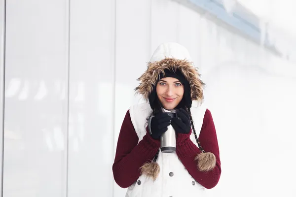 Beautiful smiling girl holding thermos in snowy winter outdoors — Stock Photo, Image