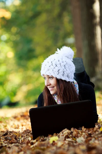 Belle jeune fille avec ordinateur portable dans le parc d'automne. Jeune fille — Photo