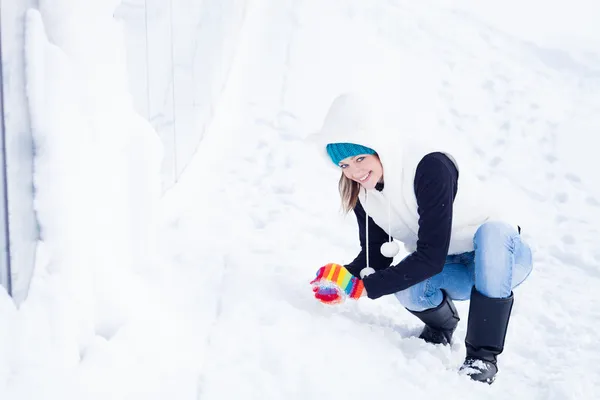 Hermosa chica en ropa de invierno preparando bola de nieve . Imágenes de stock libres de derechos
